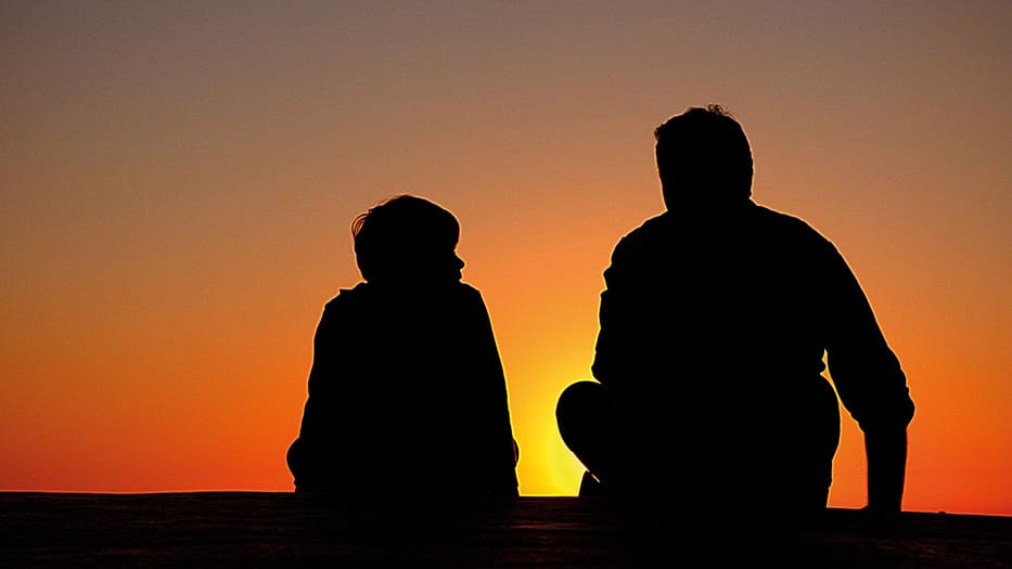 Padre e hijo hablando en una puesta de sol
