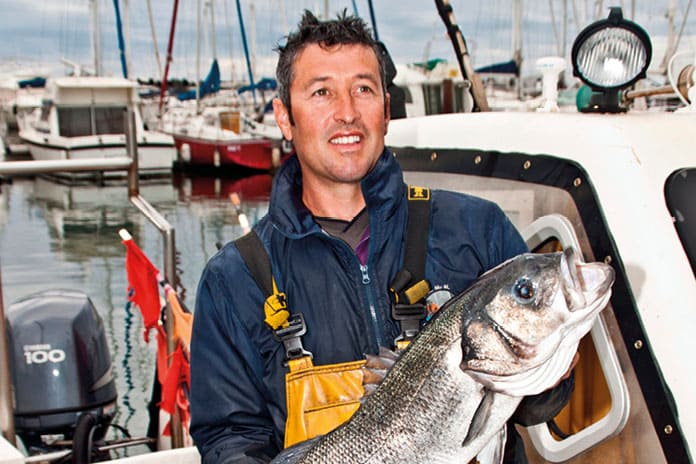 Pescador muestra un bacalao como símbolo del laico cristiano firme en su misión, incluso en entornos hostiles.