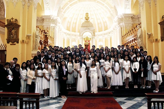Jóvenes universitarios confirmandos junto al arzobispo de Arequipa tras la ceremonia en la catedral.
