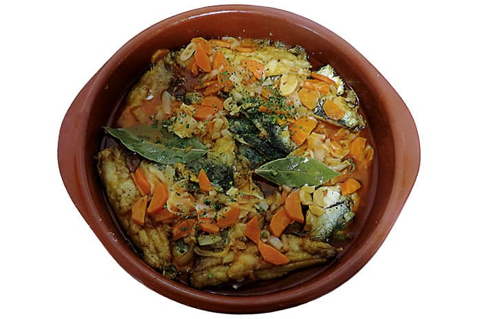 Cazuela de barro con sardinas escabechadas caseras, acompañadas de zanahorias y cebolla.