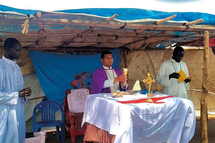 Sacerdote africano celebrando misa en una comunidad rural, rodeado de fieles.
