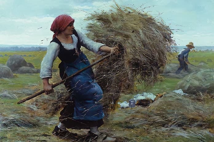 Campesina elevando heno con una horquilla en un campo, símbolo del esfuerzo cotidiano y la dignidad del trabajo