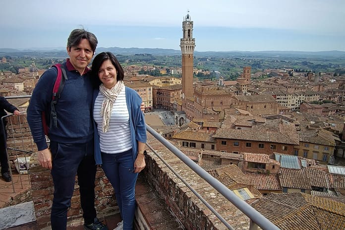 José Miguel de la Peña y Beatriz Lahoz posan ante la Torre del Mangia en Siena, símbolo de belleza arquitectónica italiana.