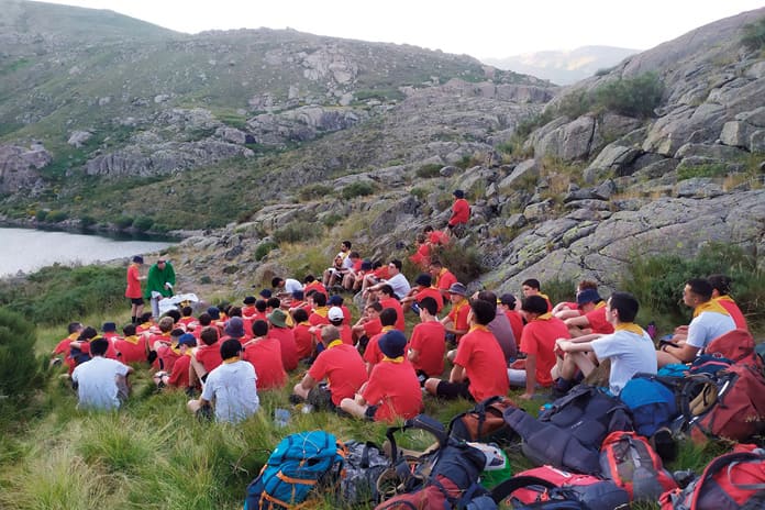 Jóvenes participando con devoción en misa al aire libre en el circo de Gredos, celebrando su fe y cercanía a la Virgen.