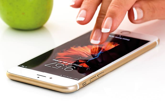 Mano tocando la pantalla de un teléfono móvil, simbolizando el uso cotidiano de la tecnología.
