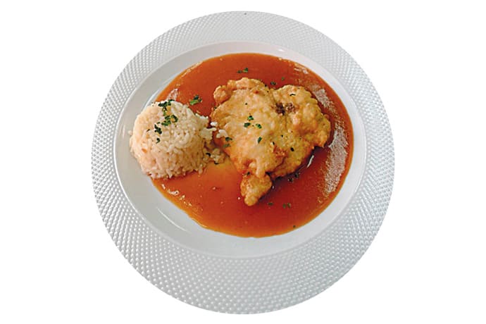 Plato de rape a la americana servido con salsa y arroz pilaw.