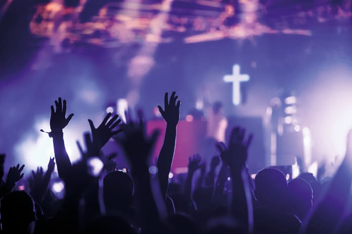 Jóvenes levantan las manos en un concierto, símbolo de búsqueda espiritual y sentido en la cultura contemporánea