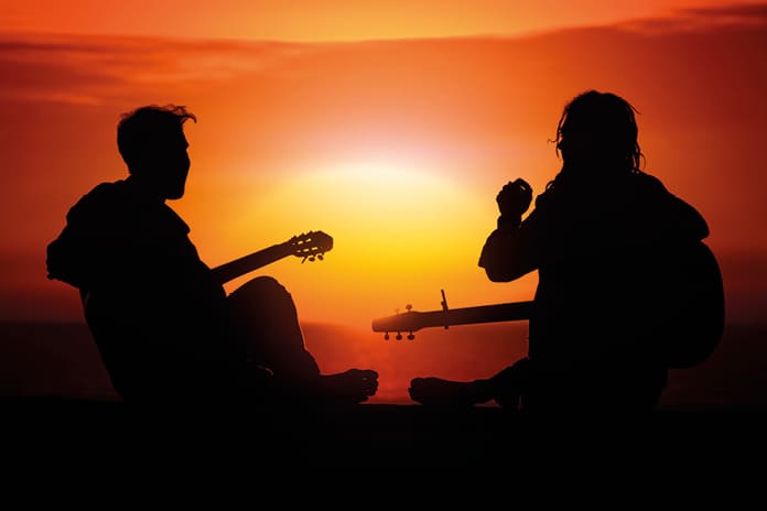 Dos jóvenes con guitarras al atardecer, símbolo del resurgir espiritual y católico entre las nuevas generaciones