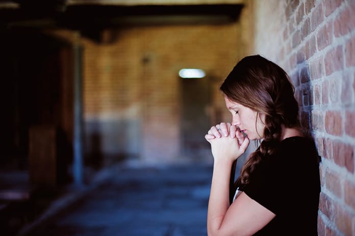 Joven rezando en silencio, expresión de fe personal y búsqueda espiritual
