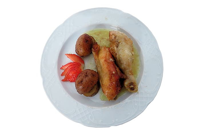 Pollo asado al horno con patatas doradas servido en fuente